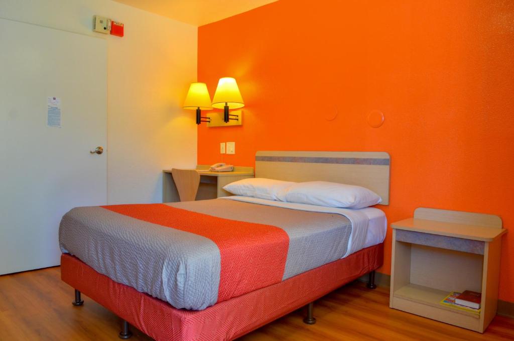 a bed in a room with an orange wall at Motel 6-Santa Nella, CA - Los Banos - Interstate 5 in Santa Nella