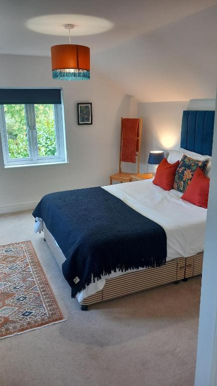 a bedroom with a large bed with red pillows at Longhurst House Annexe in Staplehurst