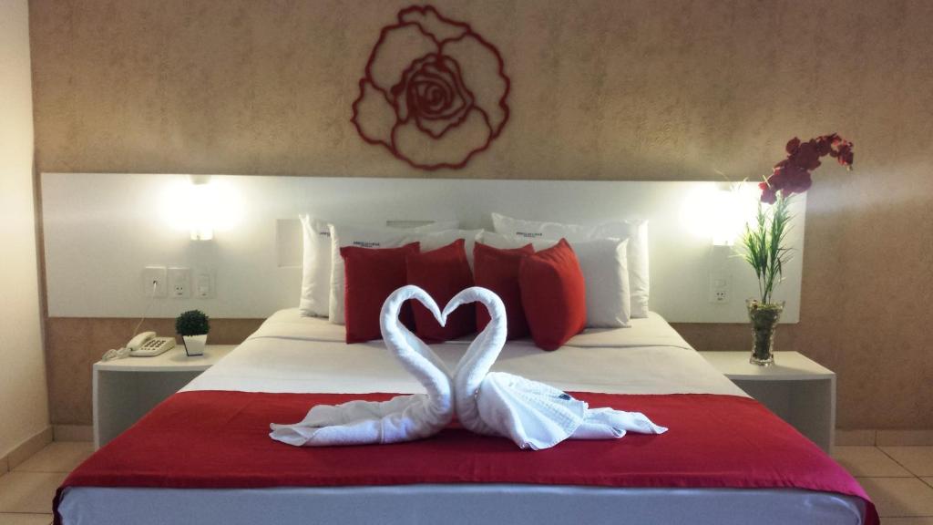 two white swans are forming a heart on a bed at Pousada Perola Dourada Maceió in Maceió