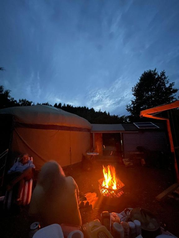 a person laying around a fire in a tent at Hillside Retreats in Machynlleth
