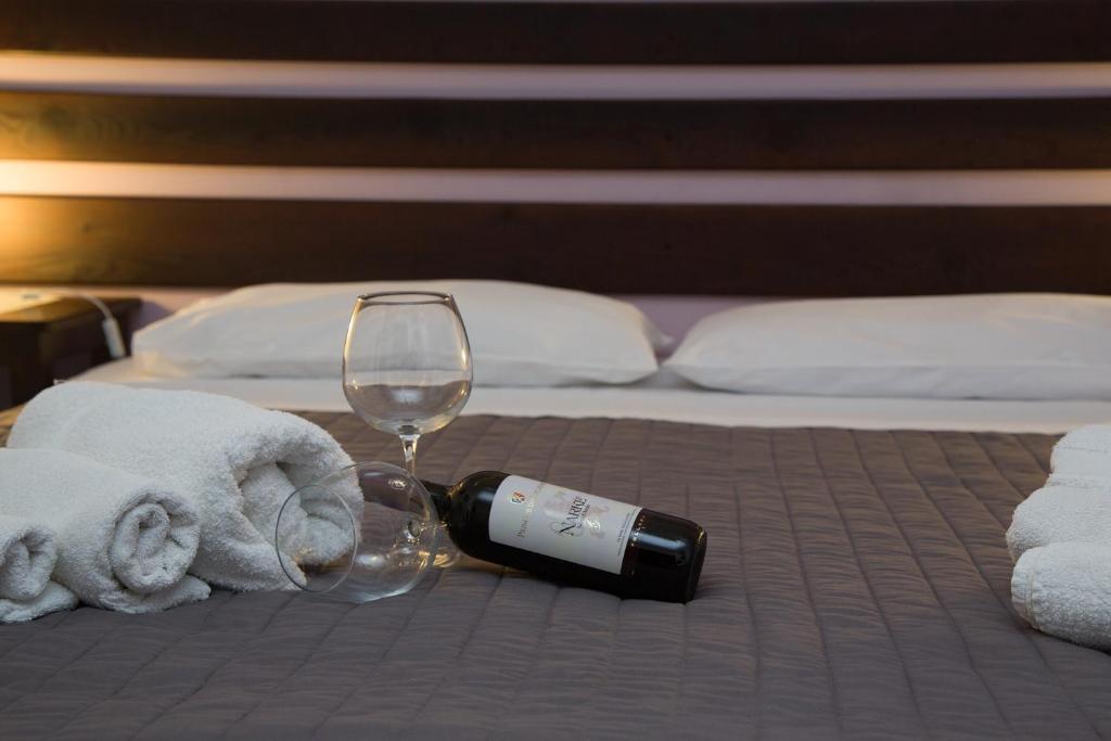 a bottle of wine and a glass on a bed at Le Terrazze Di Don Mariano in Cinisi