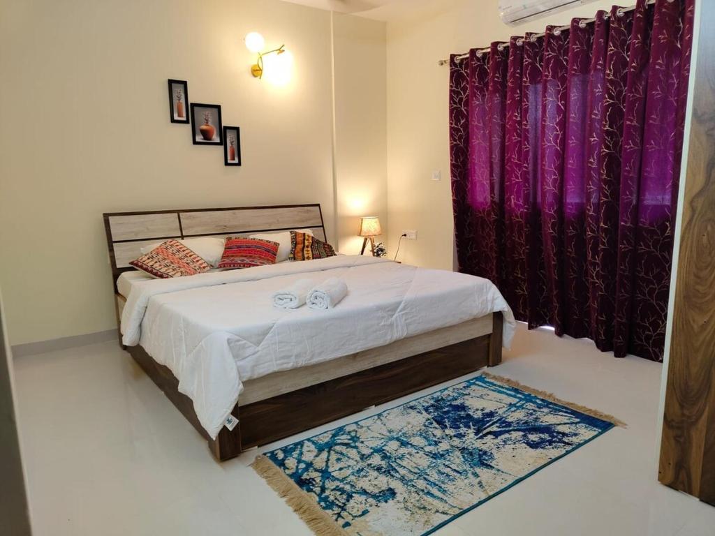 1 dormitorio con 1 cama con cortinas moradas y alfombra en Marvic Homes, en Siolim