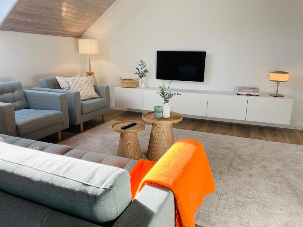 Una sala de estar con un sofá y un televisor. en Urlaub in der Eifel am Rursee - Wita31, en Einruhr