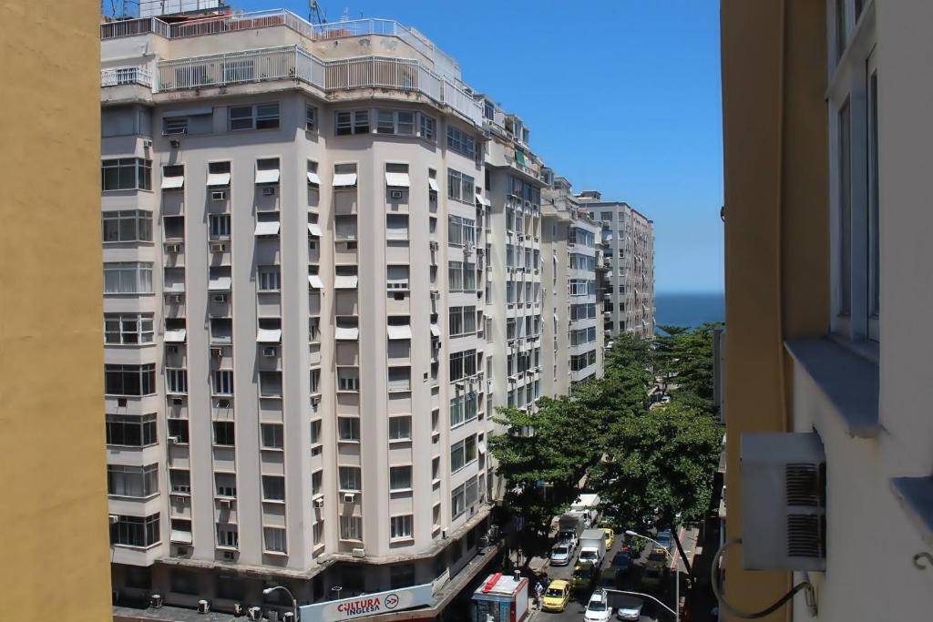 um edifício branco alto numa rua da cidade com trânsito em Coração Copacabana Figueiredo 219 no Rio de Janeiro