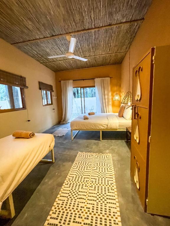 a bedroom with two beds and a ceiling at Under The Tree in Al Ḩamrāʼ