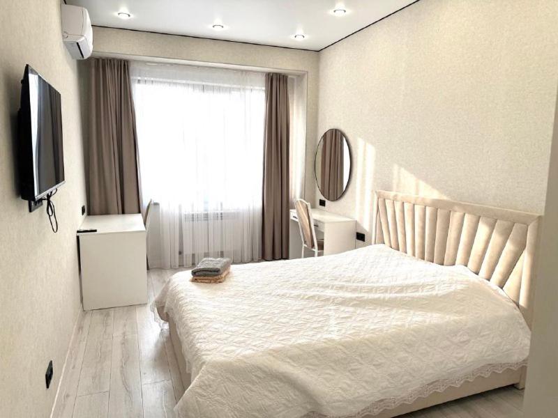 a bedroom with a white bed and a window at Жилой комплекс Космос in Bishkek