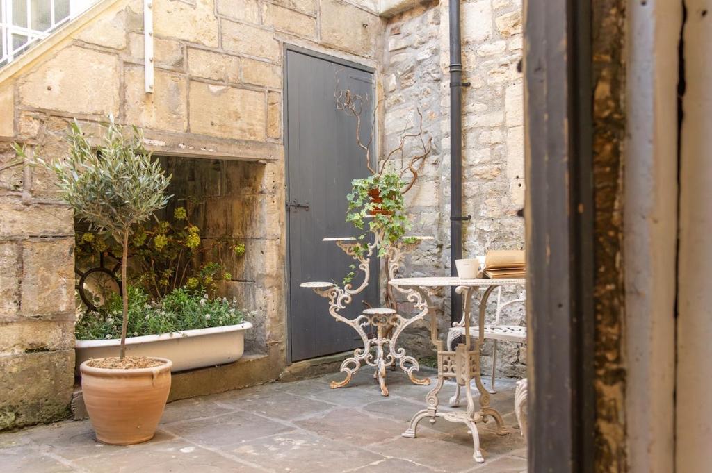 un patio avec une table, des chaises et des plantes dans l'établissement Milliners Court - One-Bed Cottage in Central Bath, à Bath
