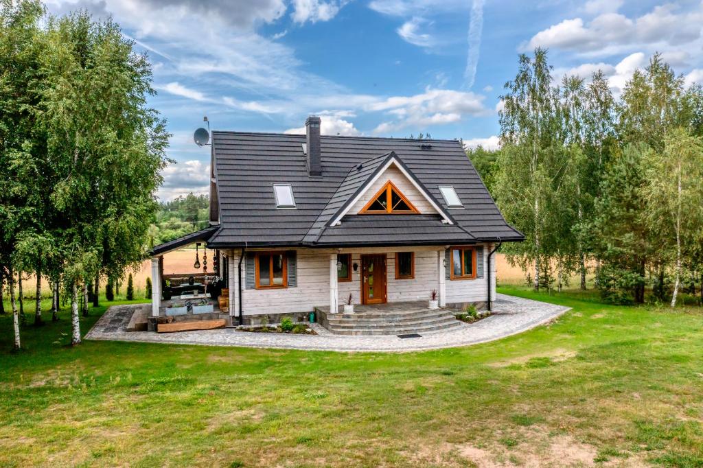 a house with a black roof on a green yard at Rodzinne wczasy nad Czarną Hańczą 