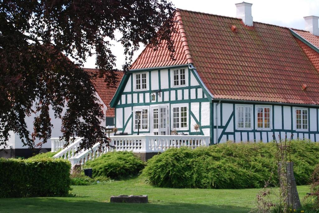 a blue and white house with a red roof at Mini-lejlighed med køkken - deler bad og toilet med nabolejlighed 2 in Asperup
