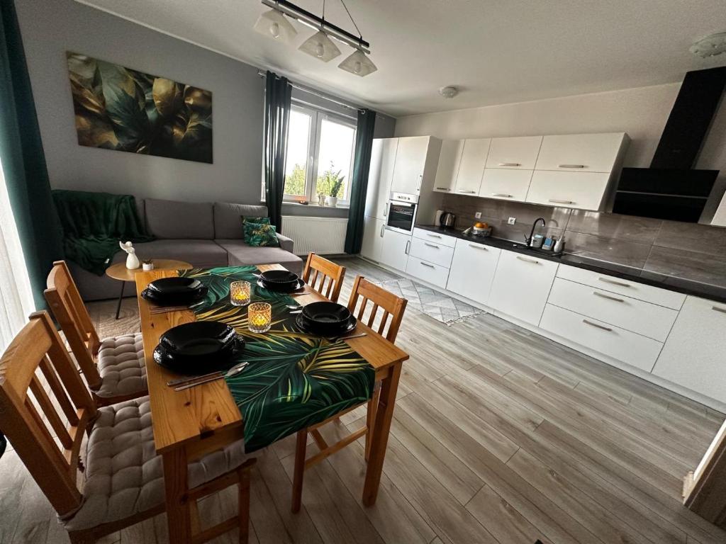 Una cocina y un comedor con mesa y sillas. en Urban Green Września,Przytulny apartament z parkingiem, en Września