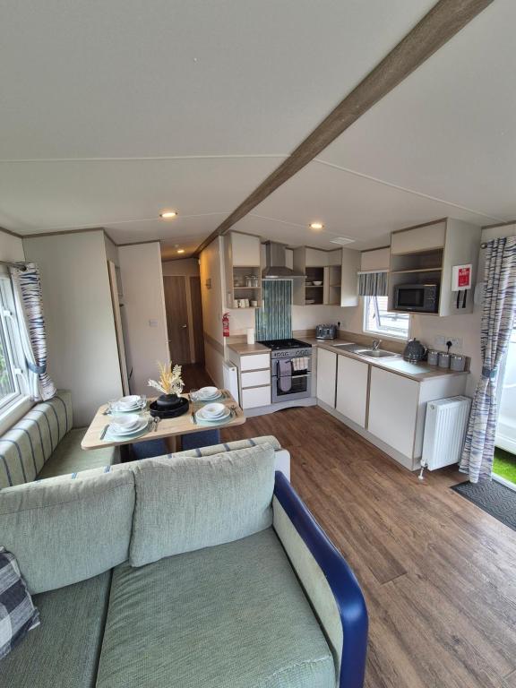 a living room with a couch and a table at Meadow Banks Combe Haven in Hastings