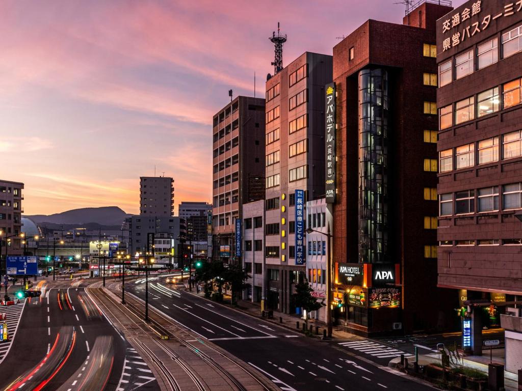 a city street with buildings and traffic at dusk at APA Hotel Nagasaki Ekimae in Nagasaki
