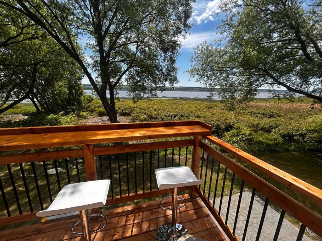 two white chairs sitting on the deck of a porch at Rives de Ste-Anne in Sainte-Anne-de-Beaupré