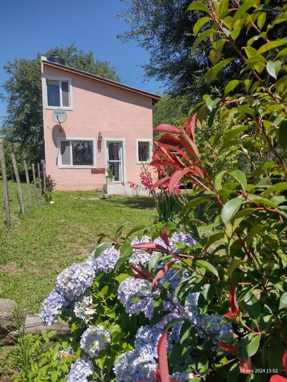 a house with a bunch of flowers in the yard at Cabañas Megustayacanto in Villa Yacanto