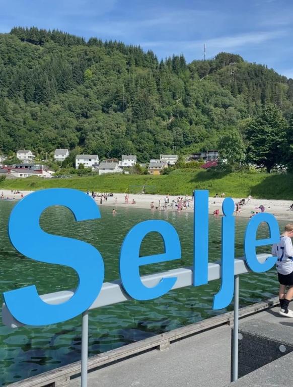 a sign at a beach with people in the water at Seljesanden Apartment in Selje