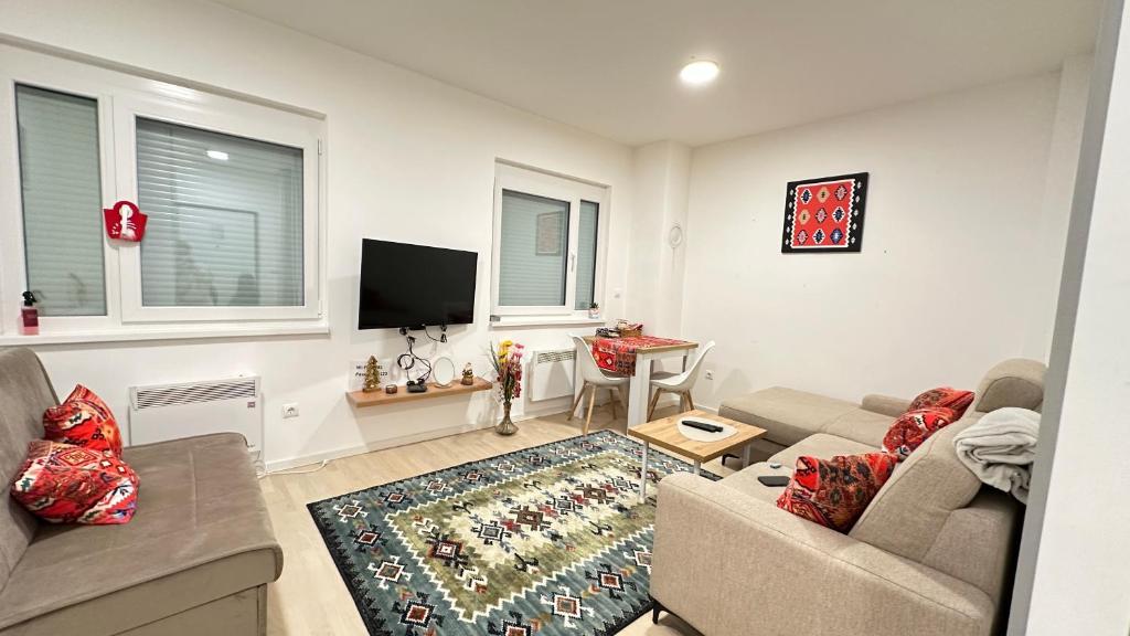 a living room with a couch and a tv at Apartman Sunce Bjelasnica in Bjelašnica
