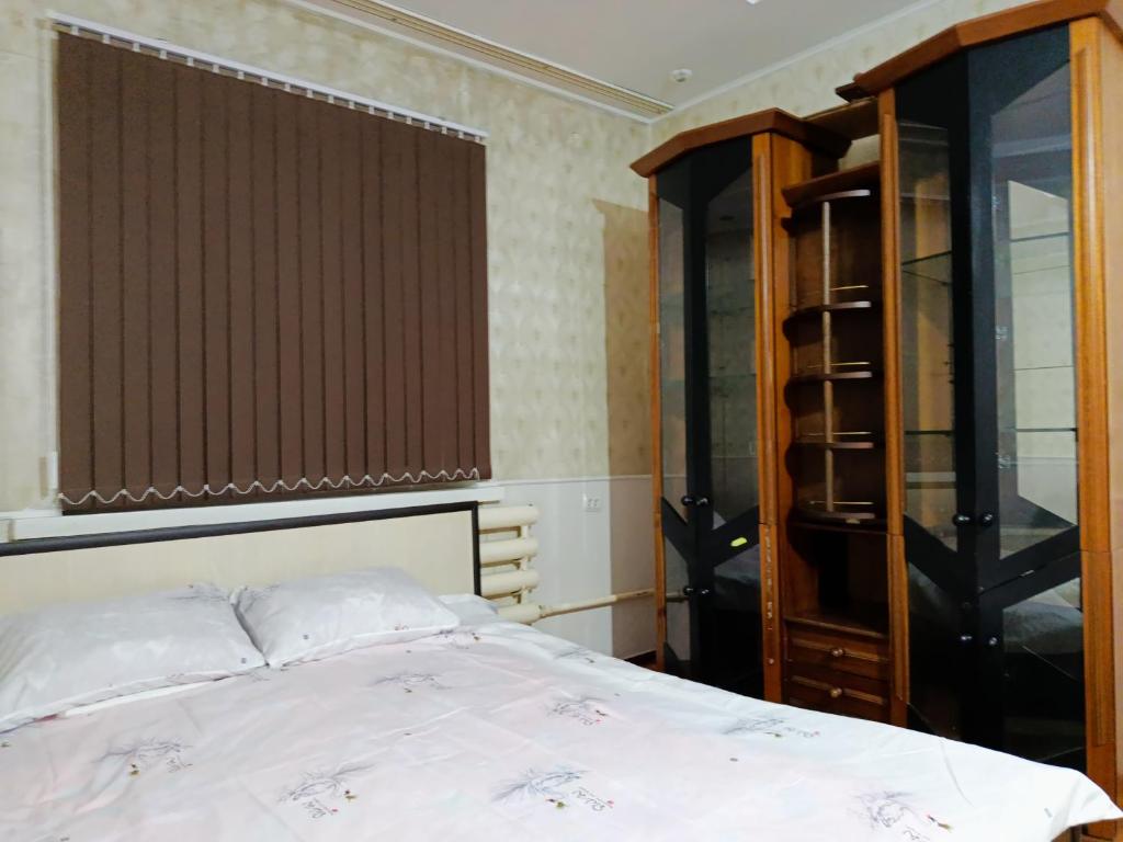 una camera da letto con un letto e un armadio in legno di Asian Home Hostel a Bishkek