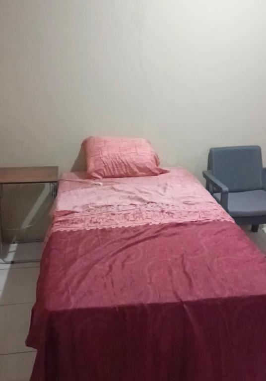 a bed with a pink blanket and a chair at Valesqui in Chiriquí