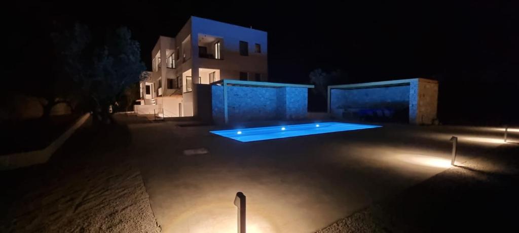 a swimming pool at night in front of a house at TAO House in Ferma