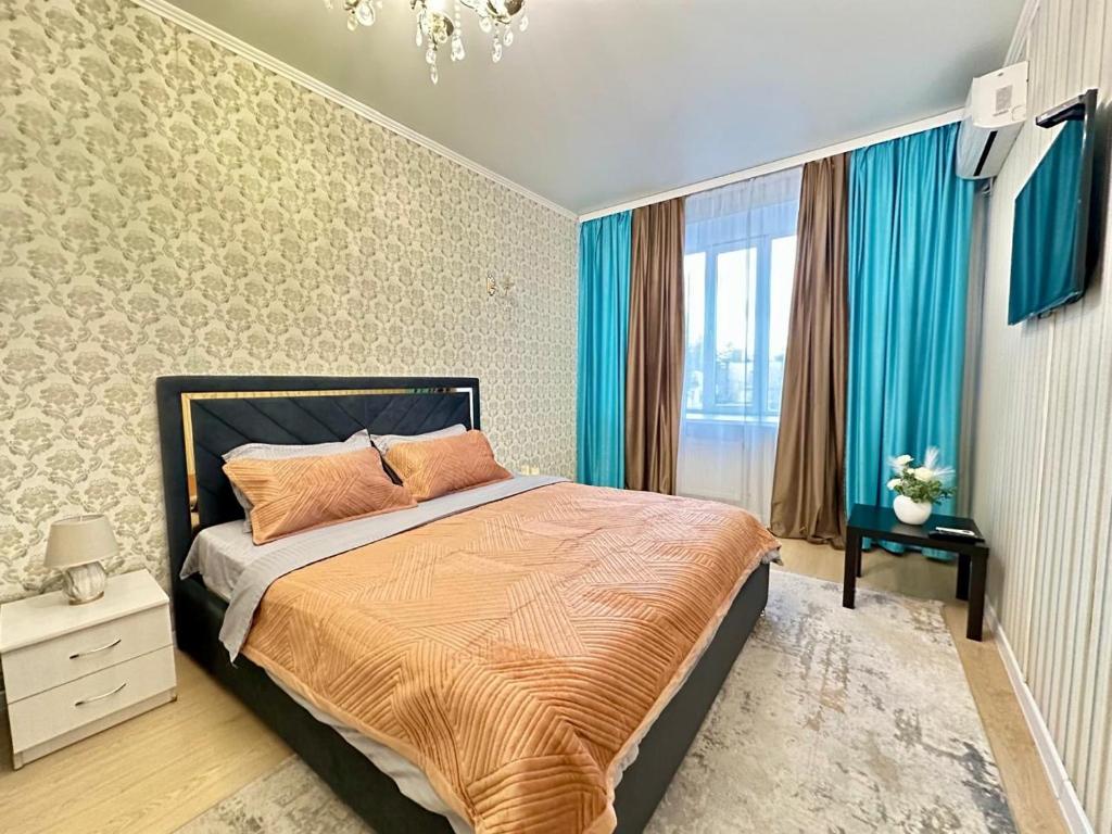 a bedroom with a large bed with blue curtains at Уютная квартира рядом с Батырмол in Pavlodar