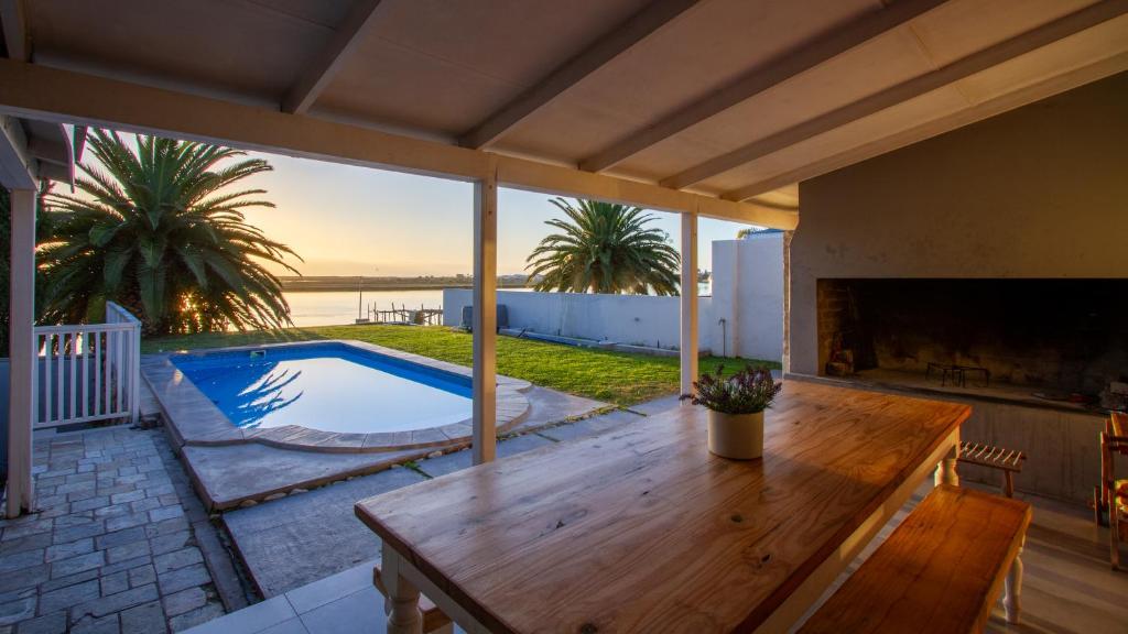 un patio con una mesa de madera y una piscina en Berg River Living, en Velddrif