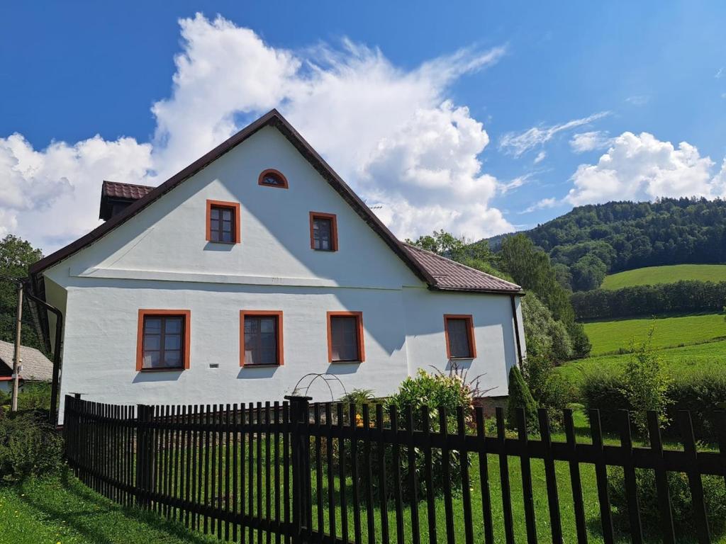une maison blanche avec une clôture devant dans l'établissement Chalupa u ztraceného potoka, à Vernířovice