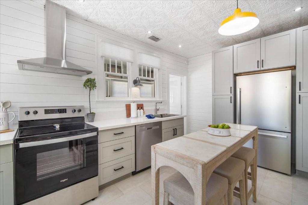a kitchen with white cabinets and a table and a stove at 2BR Bungalow Near AMI! King, W/D, Long-Stay Deals in Bradenton
