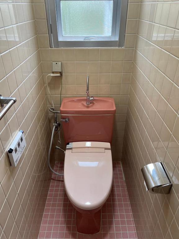 a bathroom with a toilet with a window above it at CASA de RandN Nakama 1F in Onna
