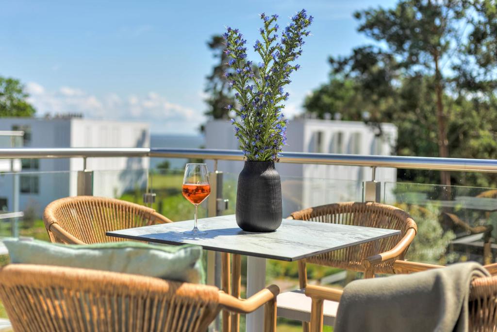 a table with a vase and a glass of wine at Apartment B10 "Südbalkon mit Haffblick" im Pine Hill Resort in Zirchow