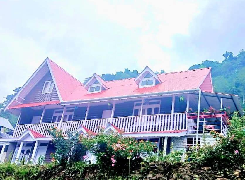 a large house with people on the balcony of it at KOLAKHAM SILVERPINE RETREAT HOMESTAY Pure Veg KOLAKHAM,LAVA in Lava