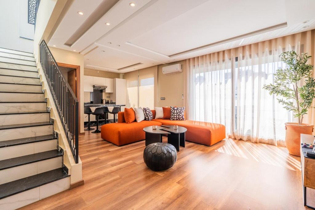 a living room with an orange couch and a staircase at Résidence Dunkerque - Duplex in Casablanca