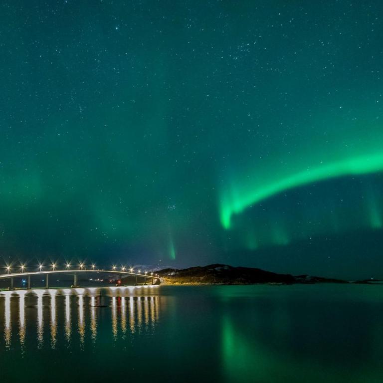 an aurora over a bridge over a body of water at Sommarøy Apartment 2nd floor in Sommarøy