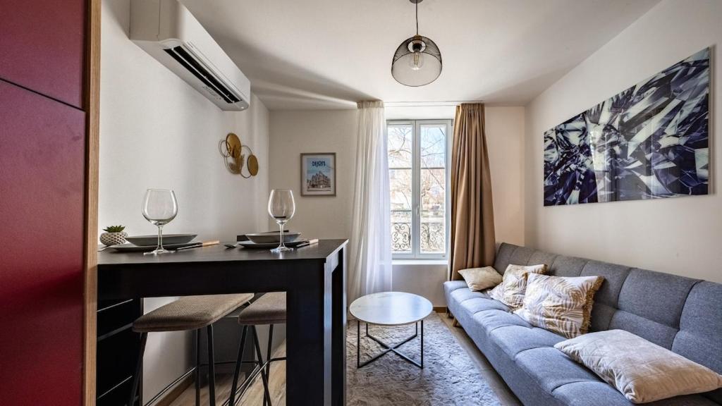 a living room with a couch and a table at Le Reflet - Vue Rivière et Caractère in Dijon