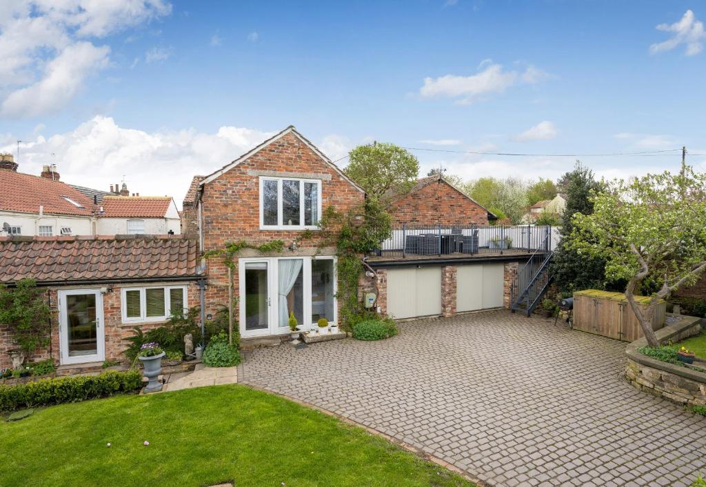 a brick house with a courtyard and a yard at Tanyard Barn - North Yorkshire in York
