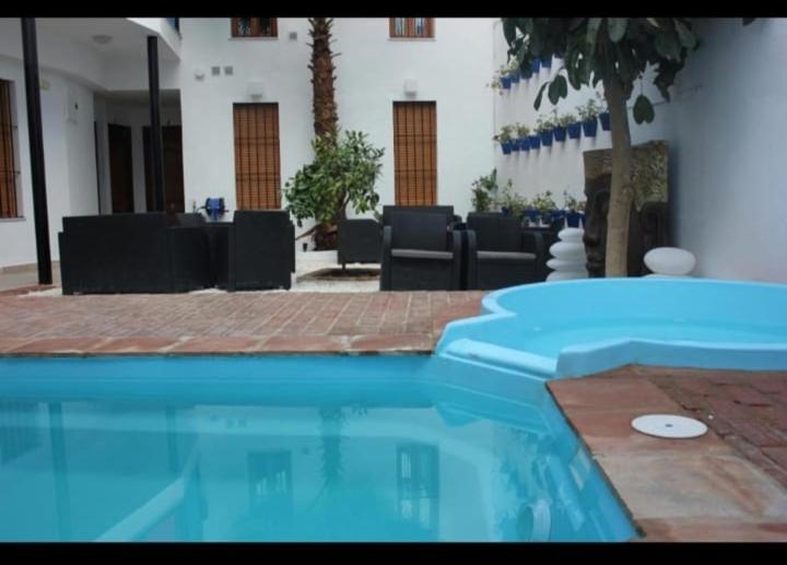 einen Pool in einem Gebäude mit Stühlen und Tischen in der Unterkunft ALFONSo XII in Córdoba