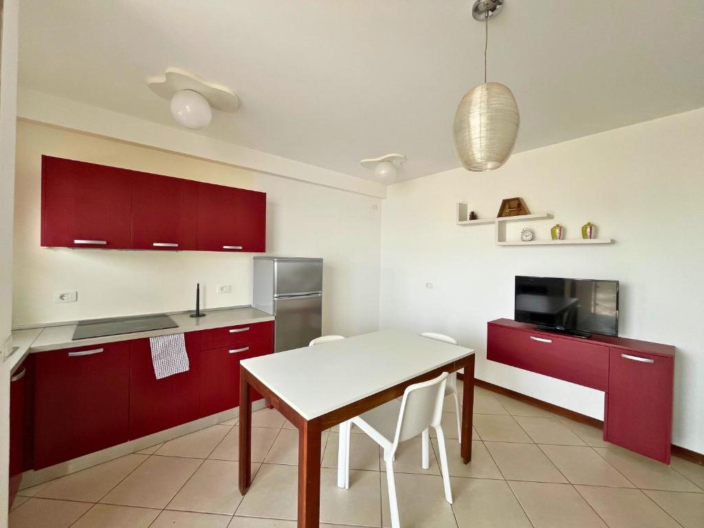 una cocina con armarios rojos y una mesa blanca en Lazareto Breeze T1, en Lazareto