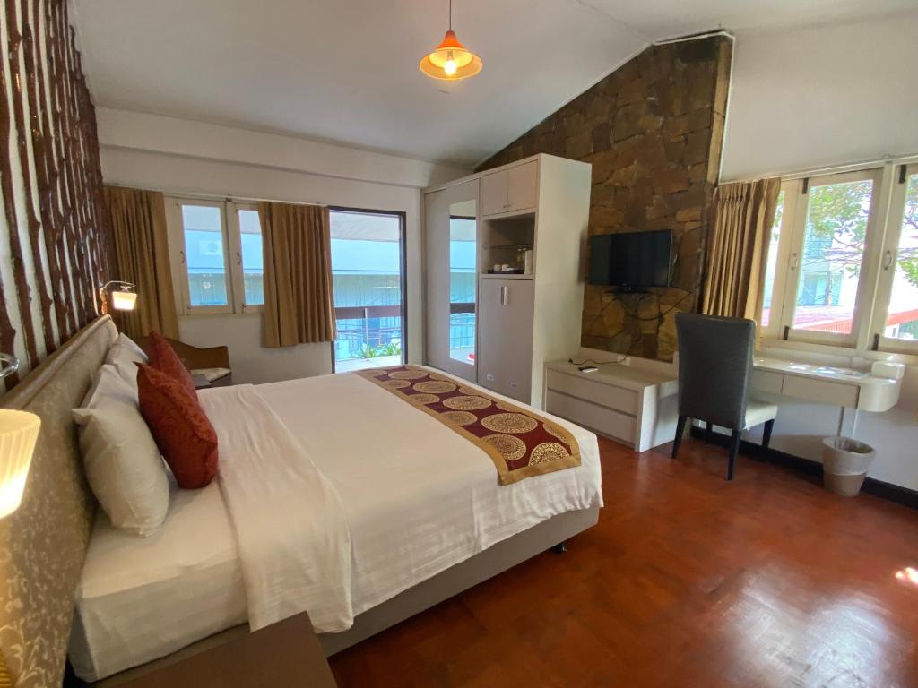 a bedroom with a bed and a desk and a table at Nautical Inn in Pattaya