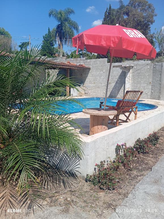 a table and an umbrella and a chair in a pool at Sítio Araújo in Ibiúna