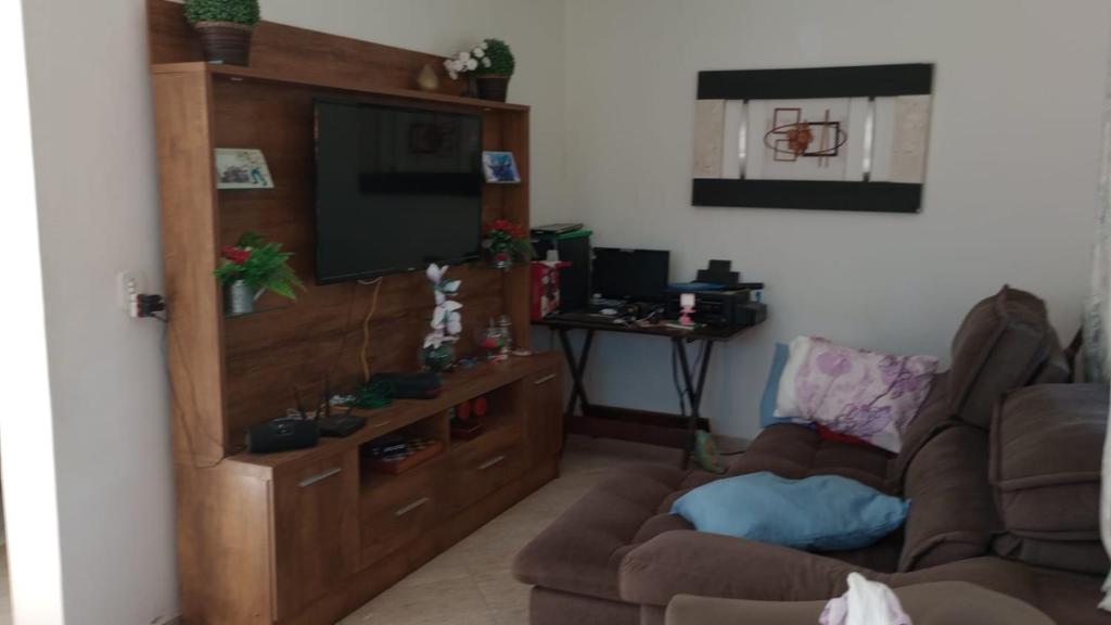 a living room with a entertainment center with a flat screen tv at Casa para temporada, São Pedro da Aldeia - RJ in São Pedro da Aldeia