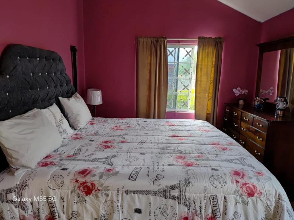 a bedroom with a large bed with pink walls at The Luxe Spot in Spanish Town