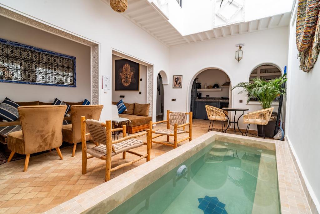 a living room with a swimming pool and a table and chairs at Riad La Kasbah secrète in Marrakech