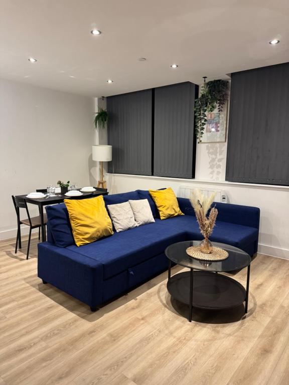 a living room with a blue couch and a table at Elegant 1 Bed Flat Near Stadium & Shops and free parking in Manchester