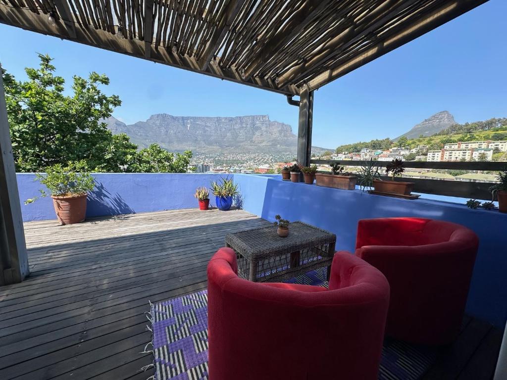 a deck with two chairs and a table and mountains at Casa Finchette rooftop apartment with panoramic views of Table Mountain in Cape Town