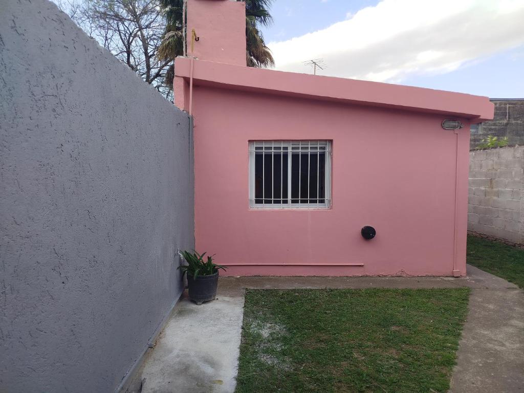 Ein rosa Haus steht neben einer Mauer in der Unterkunft Departamento Manna in Alta Gracia