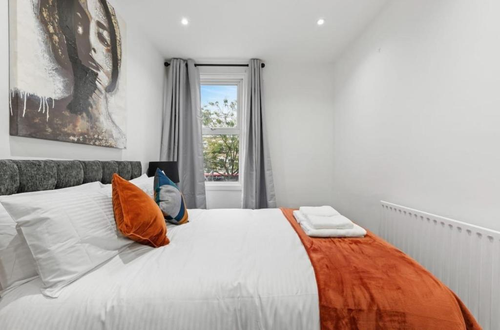 a bedroom with a bed with orange and white pillows at Amazing 1 Bedroom Flat in Central London in Moffat
