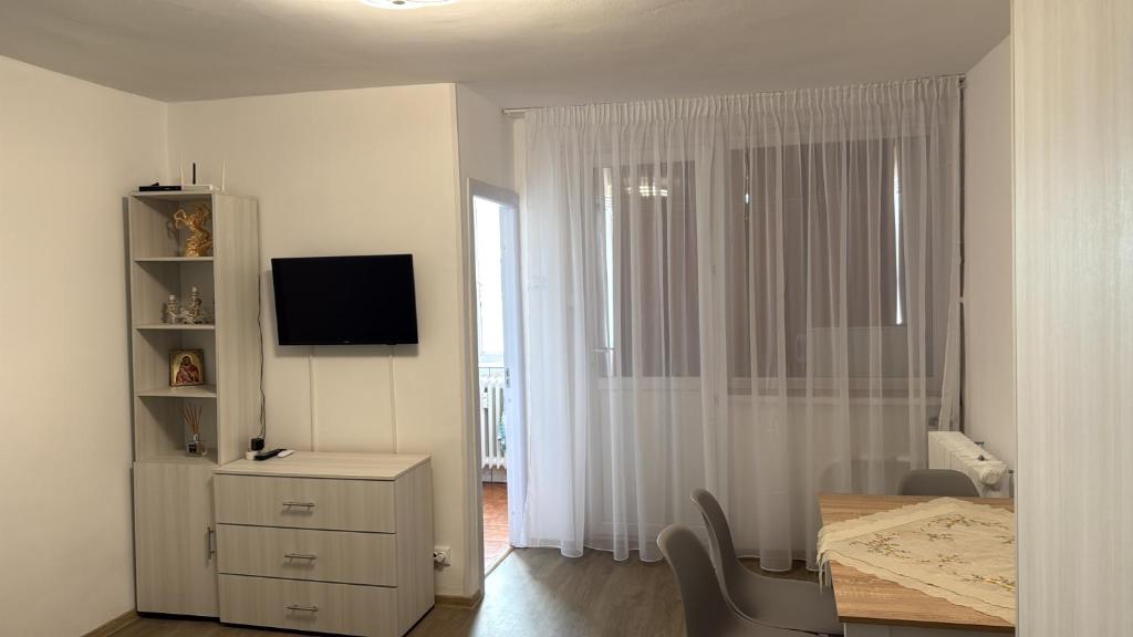 a white living room with a table and a television at Garsonieră Craiova in Craiova