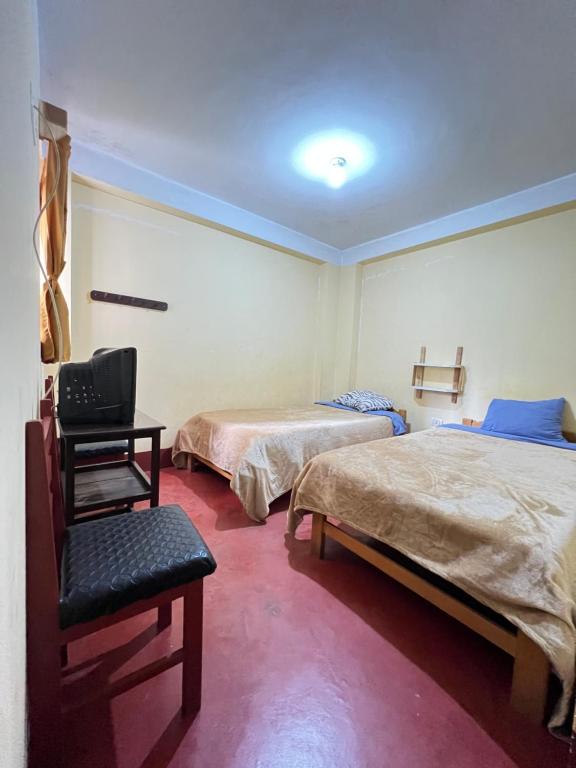 a room with two beds and a chair in it at Curahuasi Backpackers in Curahuasi