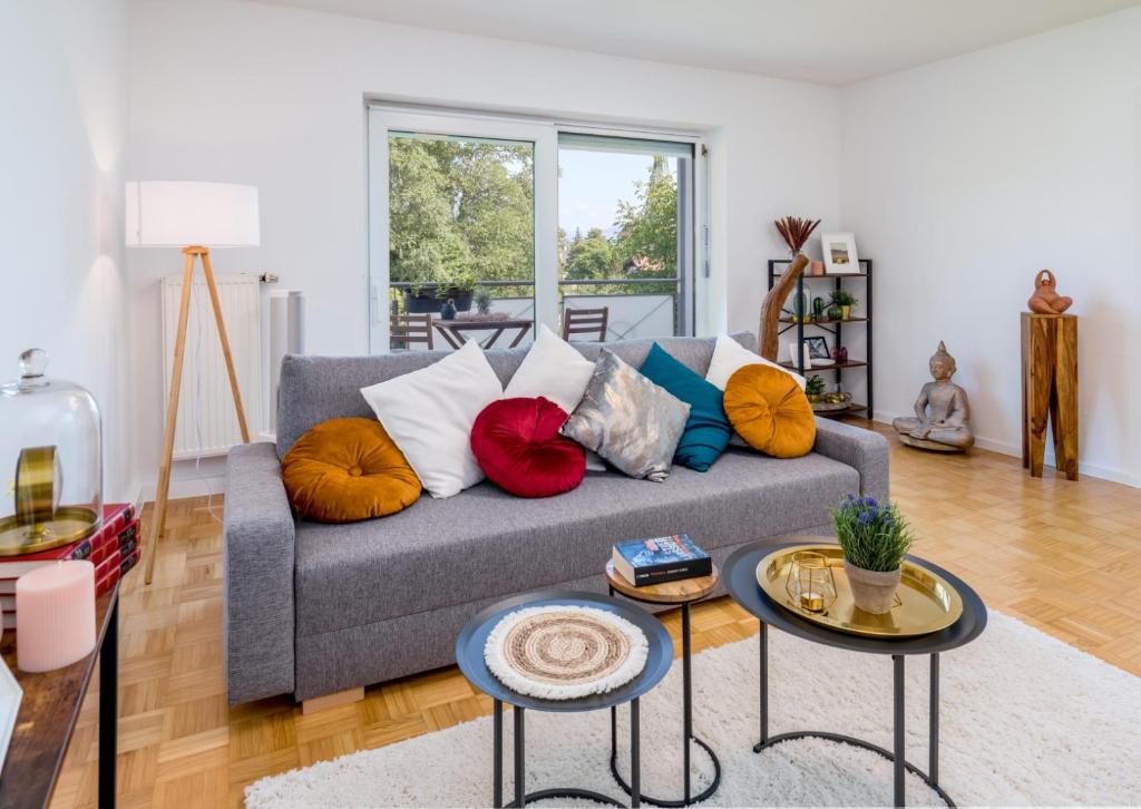 a living room with a gray couch with colorful pillows at OG2 L City Wohnung mit Balkon 15min bis Salzburg in Freilassing