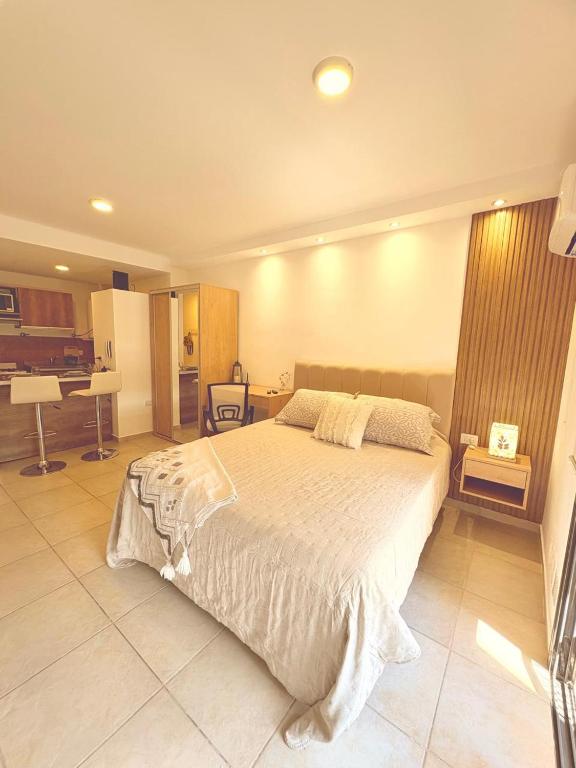 a bedroom with a large bed and a kitchen at suite urquiza in Paraná