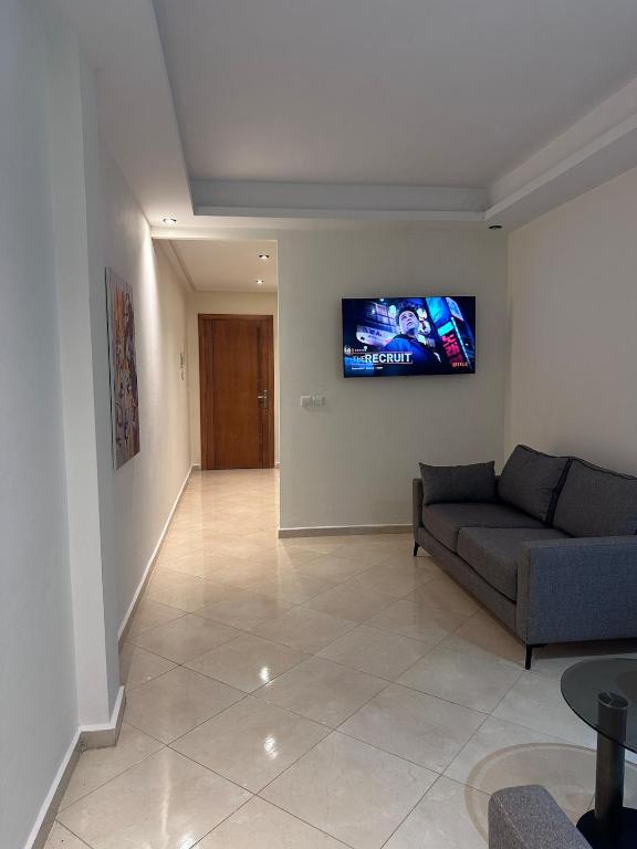 a living room with a couch and a tv on the wall at La Pause Comfort style in the center in Temara